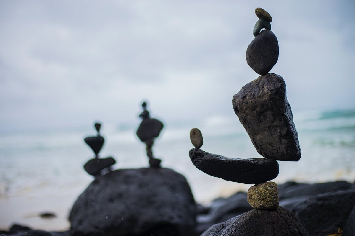 Steine sind kunstvoll aufeinander gestapelt am Strand mit unscharfem Hintergrund.