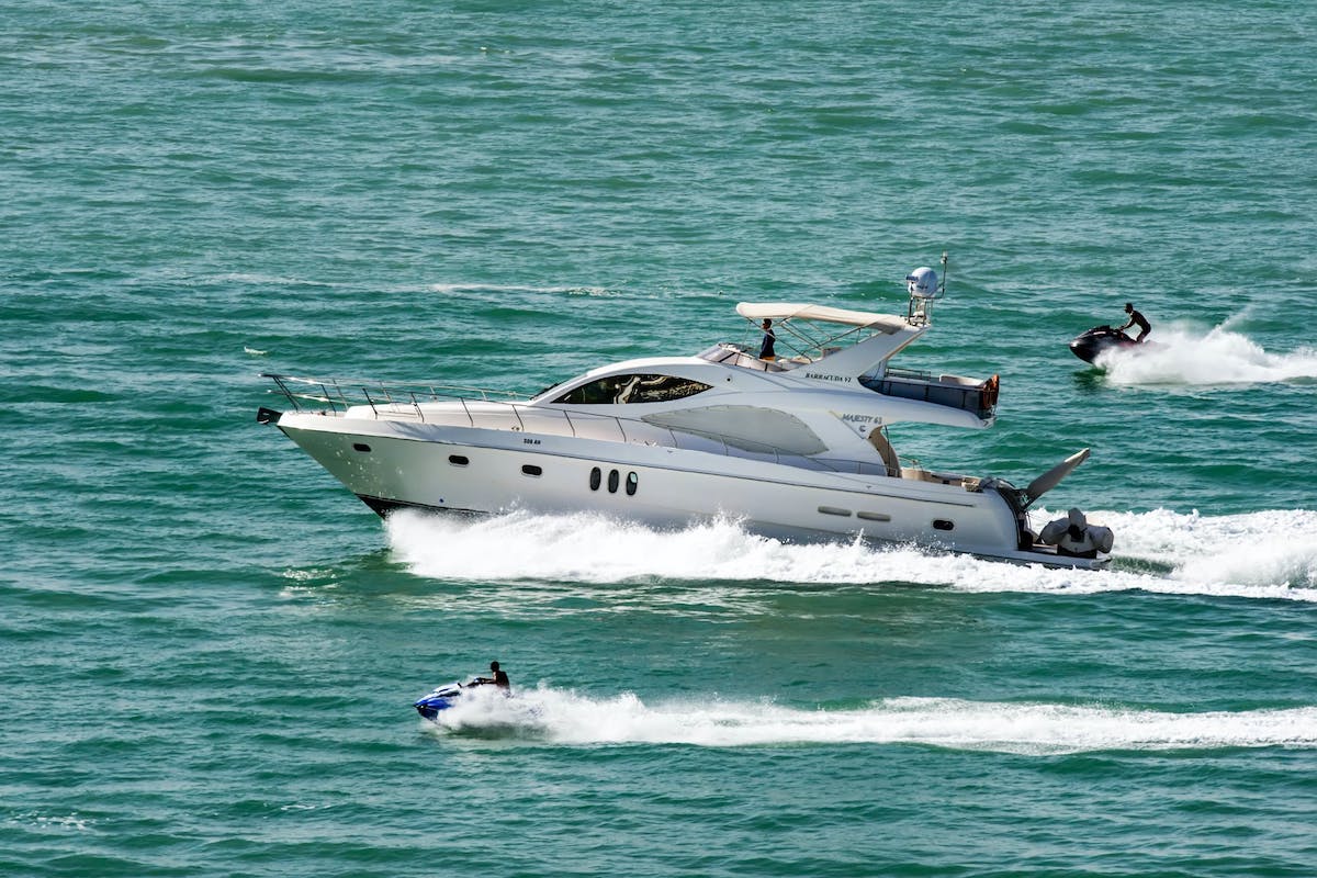 Luxusyacht fährt auf offenem Meer, begleitet von zwei Jetskis.