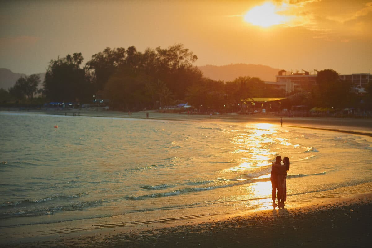 Couple silhouetted beside the sea at sunset in Chonburi