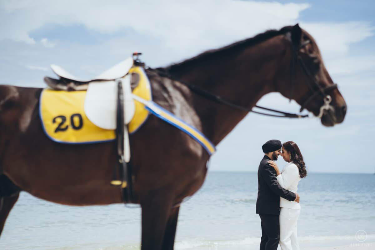 Couple with a racehorse on the beach during a pre-wedding shoot in Thailand