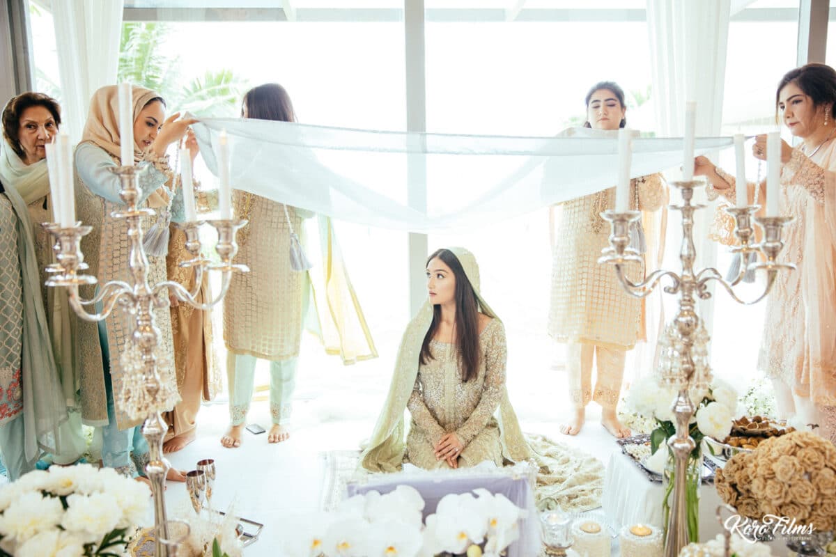 Female relatives hold a white veil over the bride during her Nikah ceremony in Hua Hin, Thailand