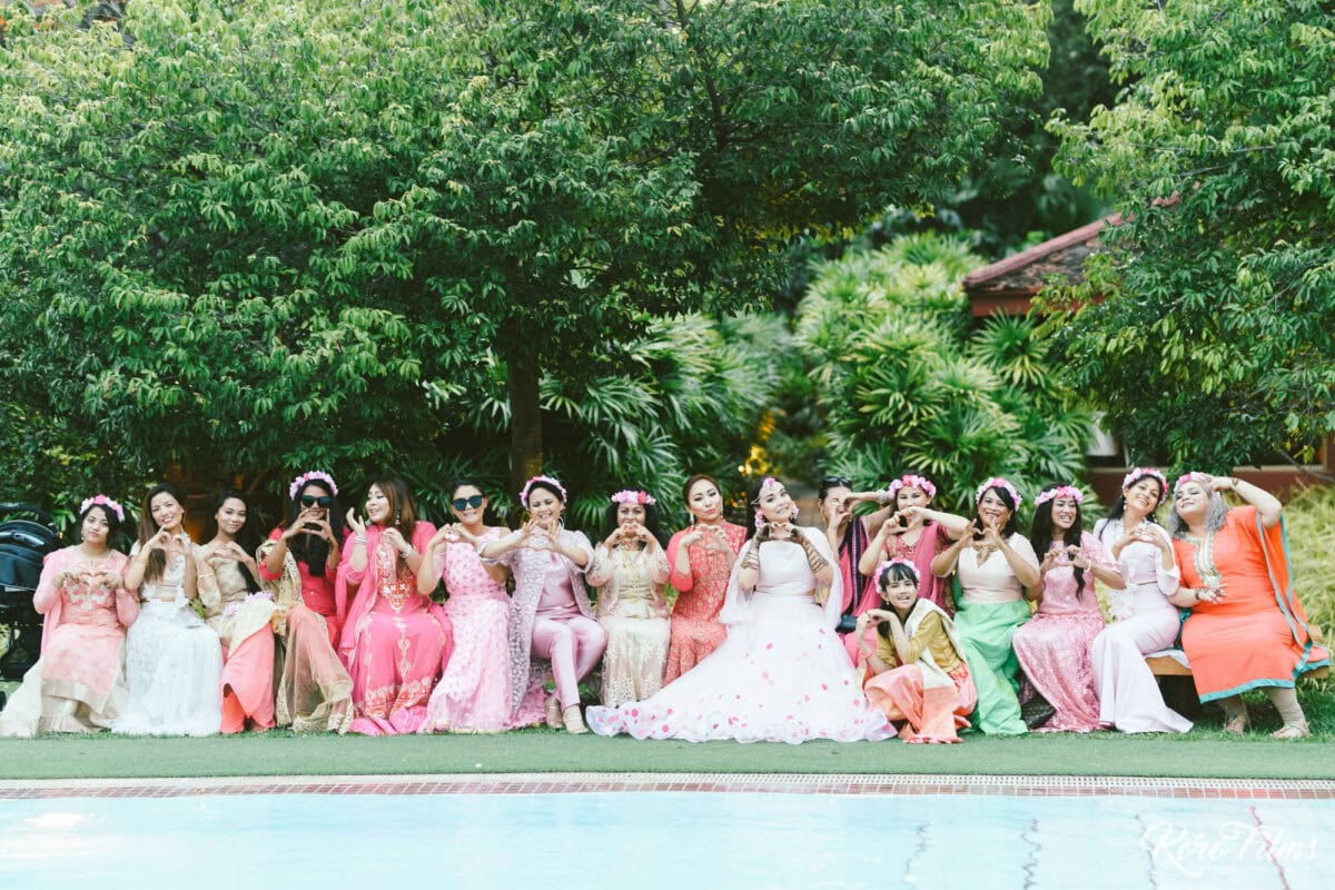 The bride and her friends in pink and lilac outfits line up by the pool at the Mehendi party in Pattaya