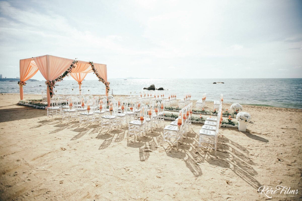 Beach mandap with peach drapes and rows of clear chairs facing the sea at Cape Dara Resort, Pattaya