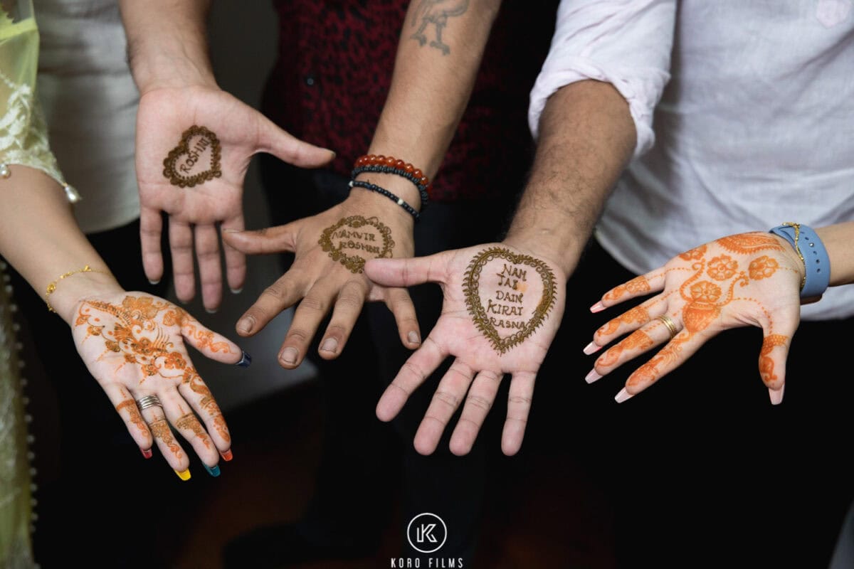 Hands with fresh mehndi designs, including the couple’s names, at a Sikh pre-wedding function in Bangkok
