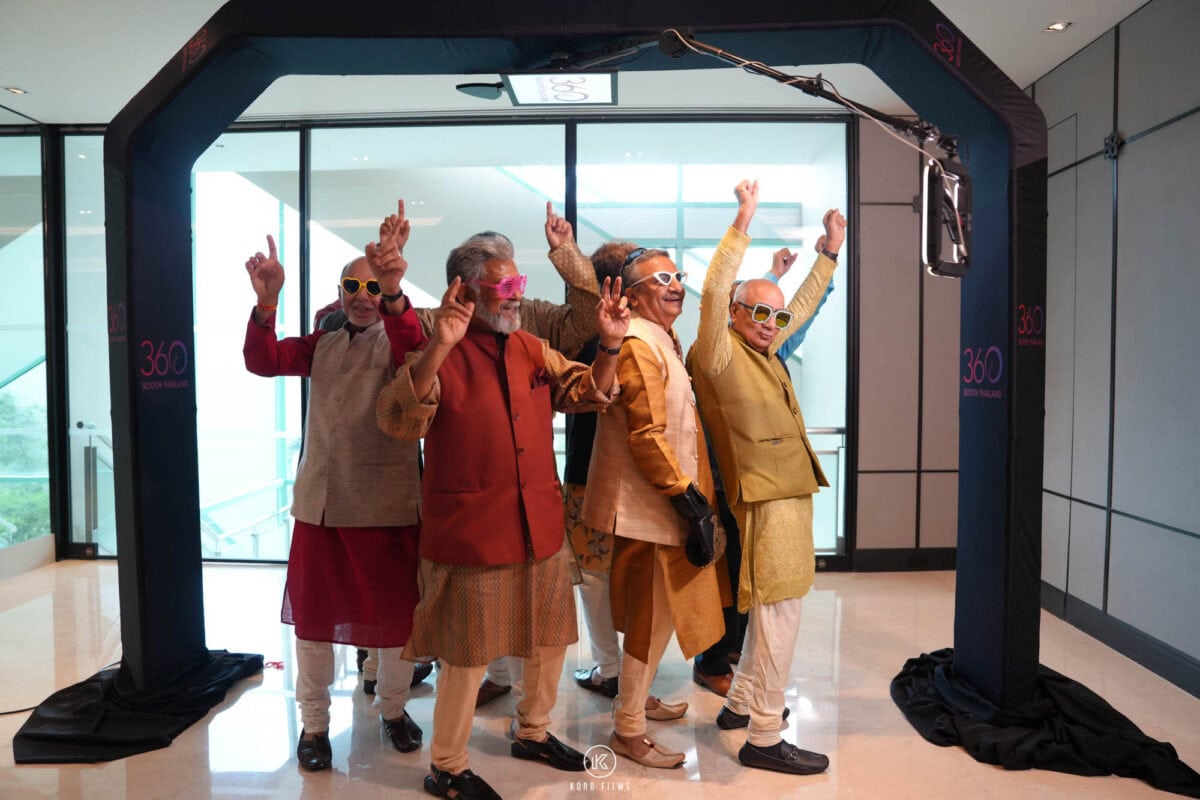 A group of guests raise their arms under the 360 overhead booth frame