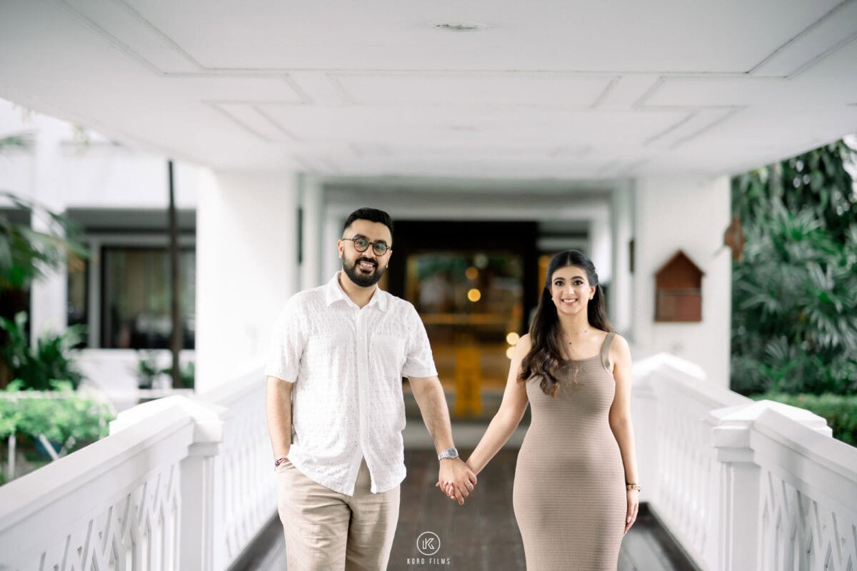 Shauna and Dhiren walk hand in hand on a white terrace at Anantara Riverside Bangkok Resort