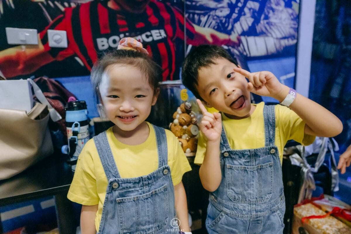 Two children in matching yellow T-shirts and denim overalls at Sara and Saku's birthday party at BOUNCE Thailand, The EmQuartier, Bangkok