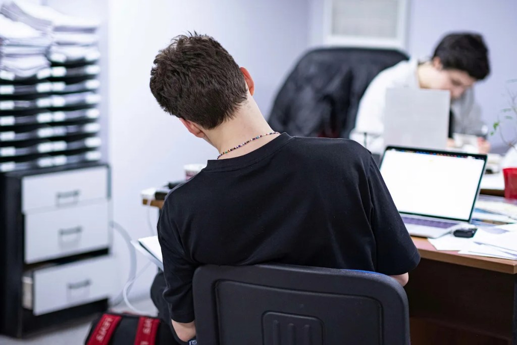 Man leaning forward at his desk to take pressure off his lower back while sitting
