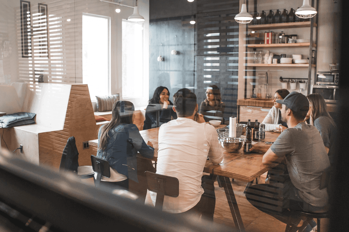 Office workers sat around kitchen table talking