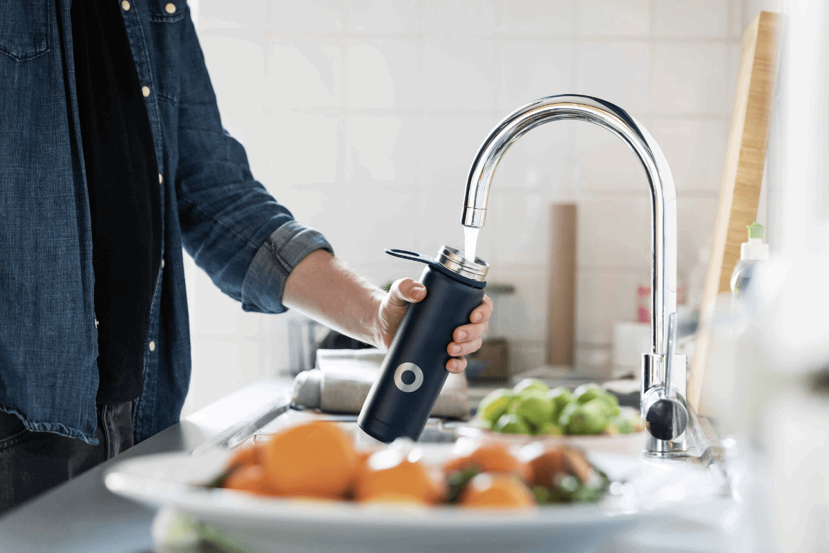 Employee filling up refillable water bottle from the office kitchen tap