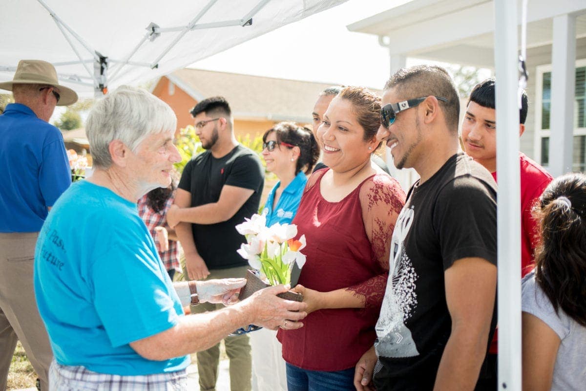 A family celebrates their home dedication with Habitat volunteers