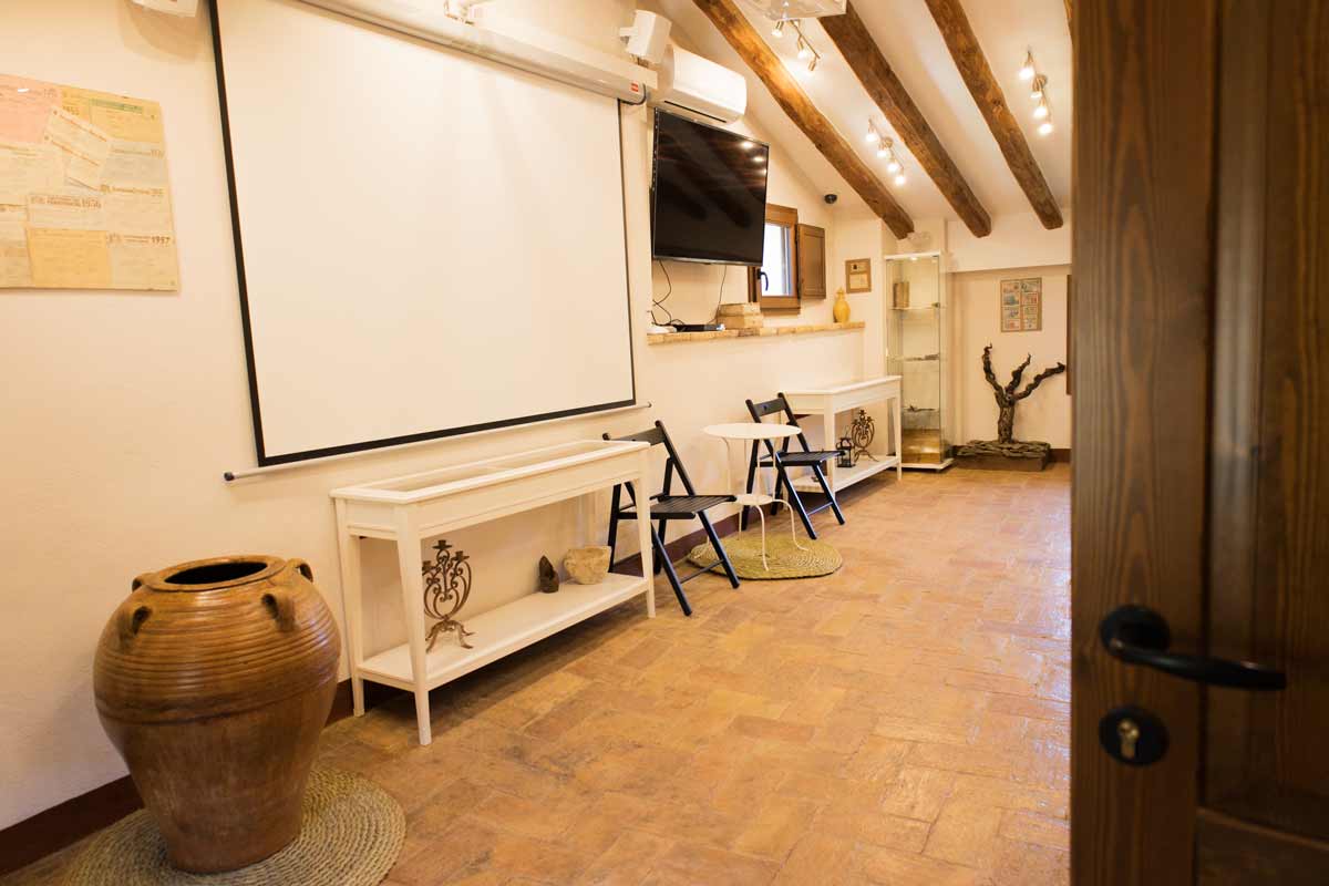 Fotografia general d'una sala àmplia equipada, on hi ha cadires, una pissarra per projectar...