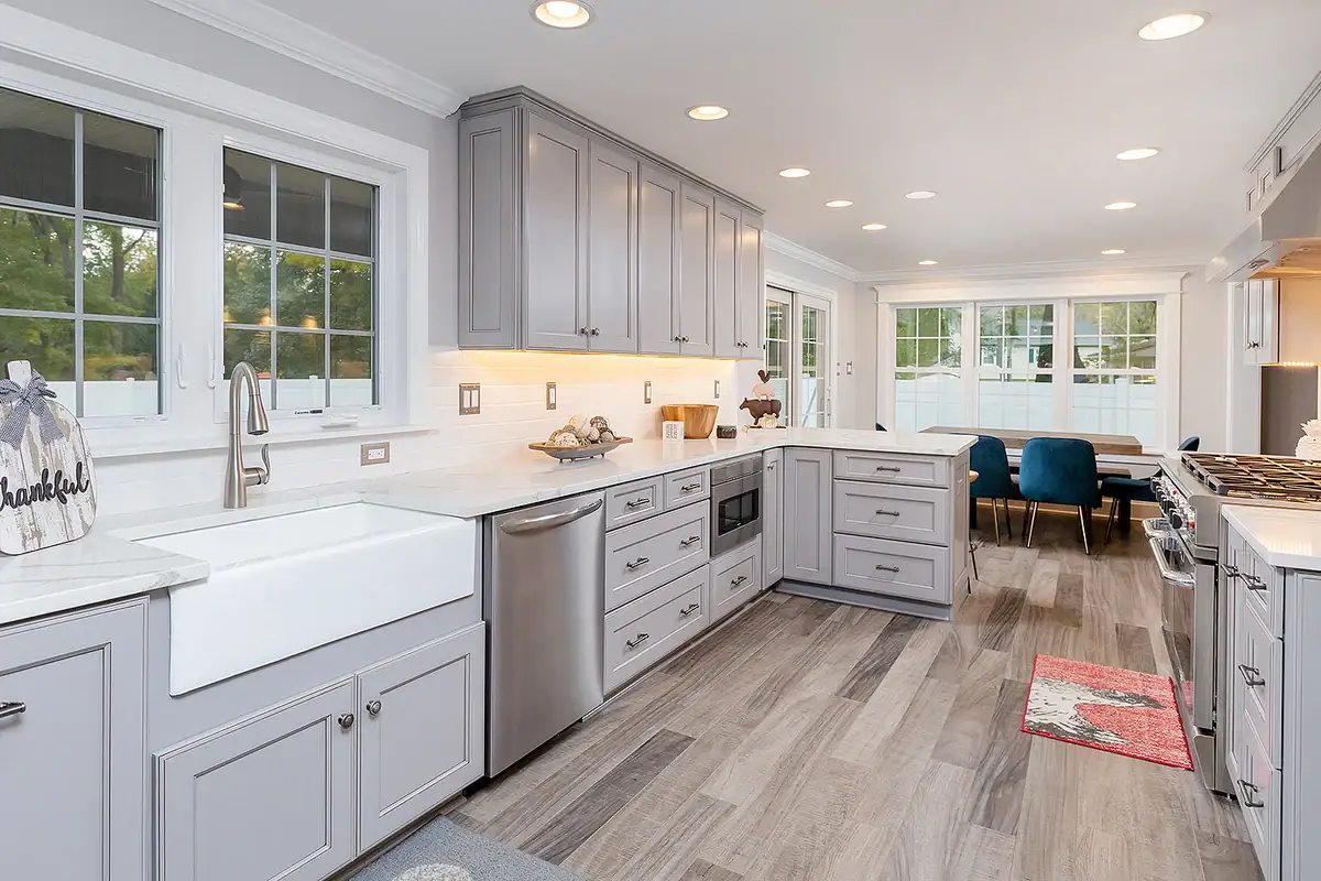 Kitchen and dining area with stainless steel appliances, white subway tile backsplash, and blue velvet dining chairs.