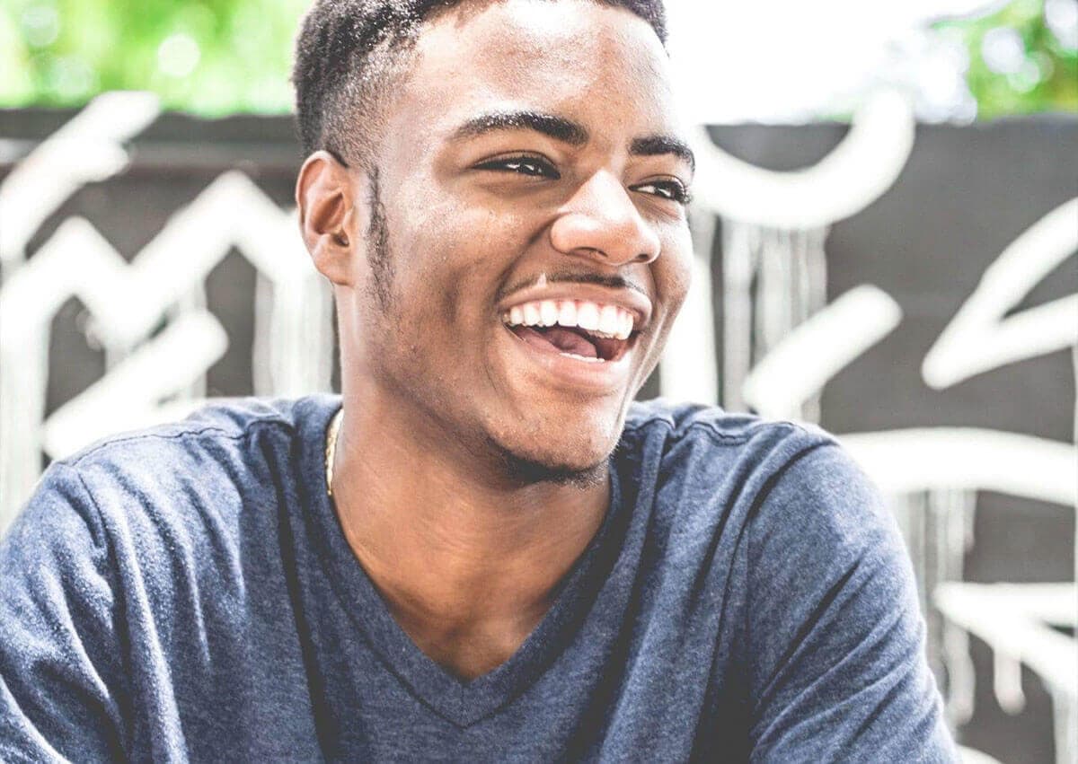 hombre con camiseta color gris oscura sonriendo