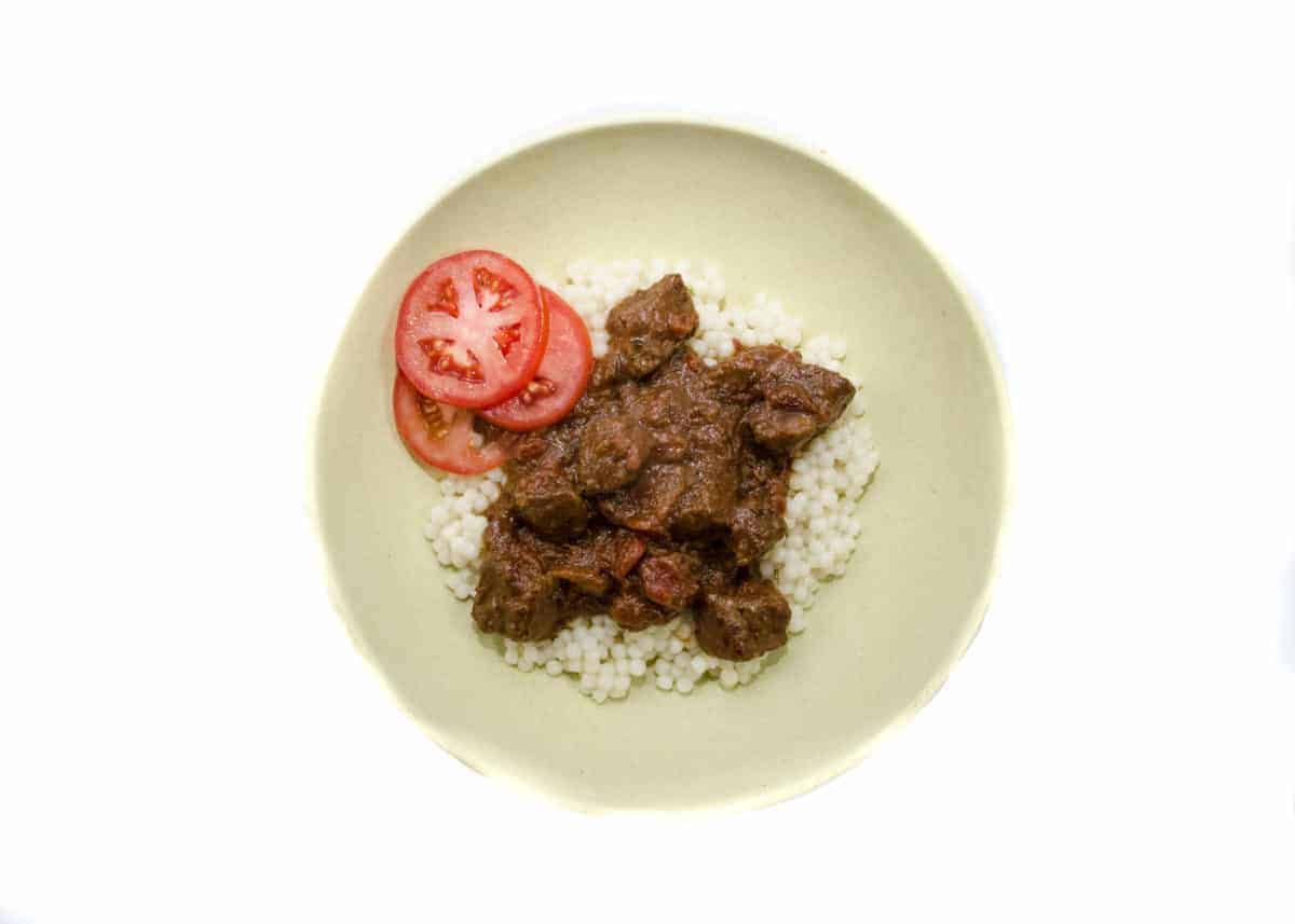 plate of couscous and meat with drunken jerk jamaican marinade