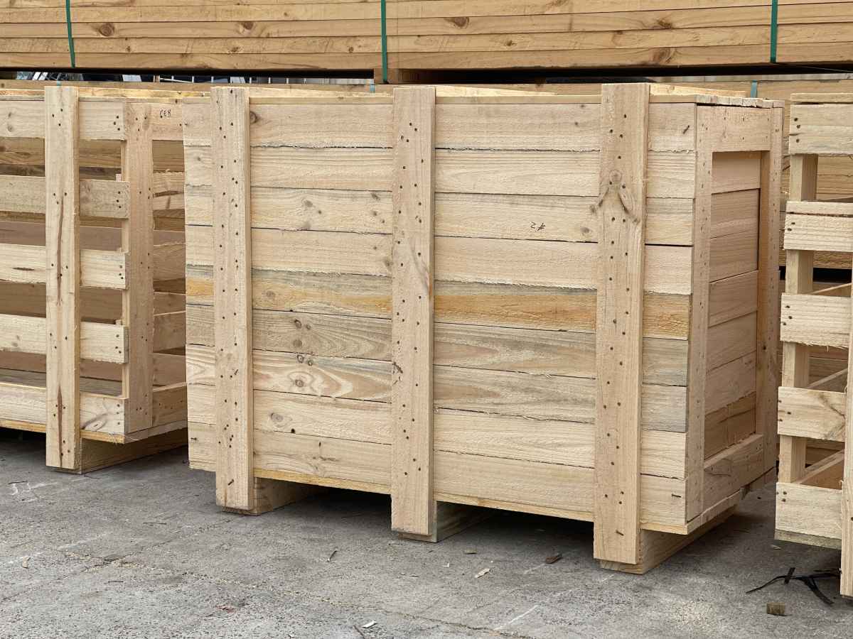 large wooden shipping case and large wooden shipping crate with stack of timber in background 1