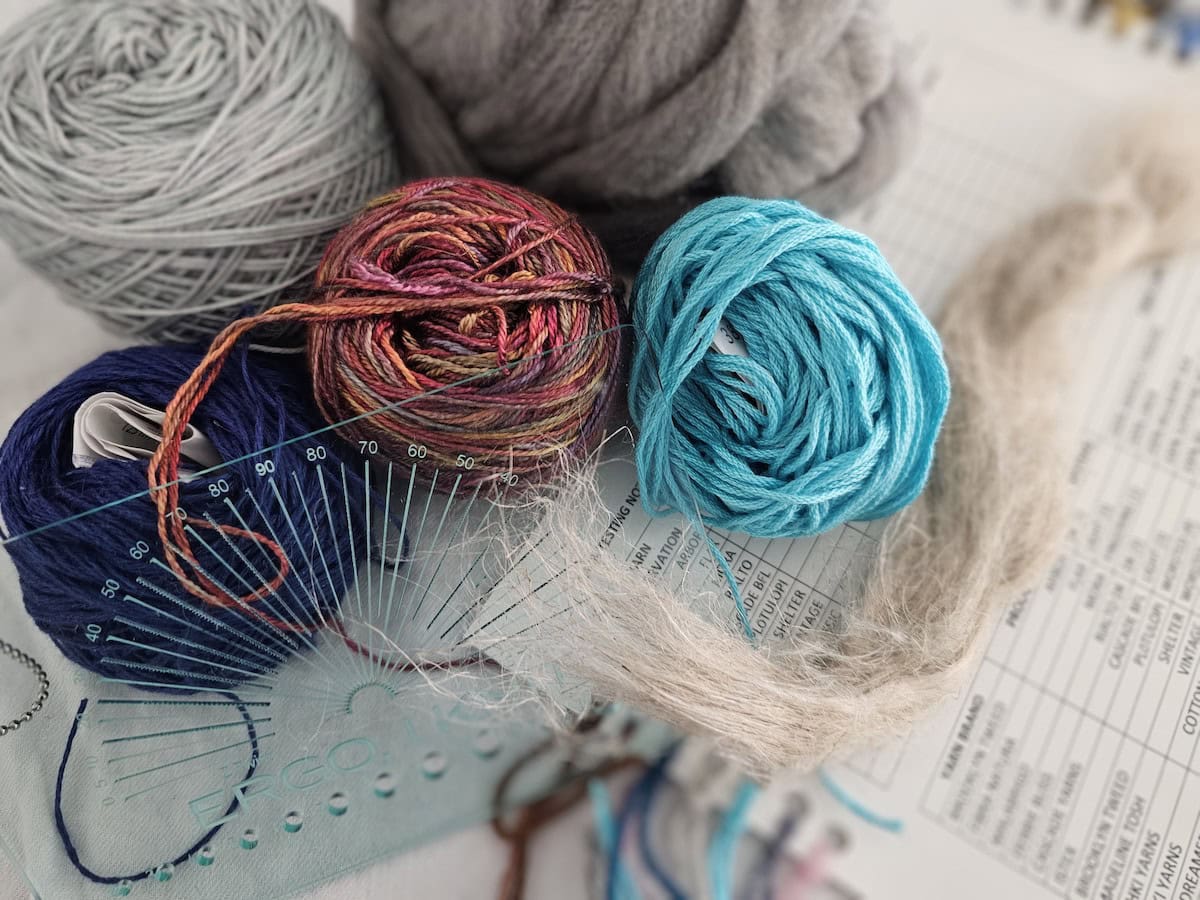 five balls of yarn with other knitting tools