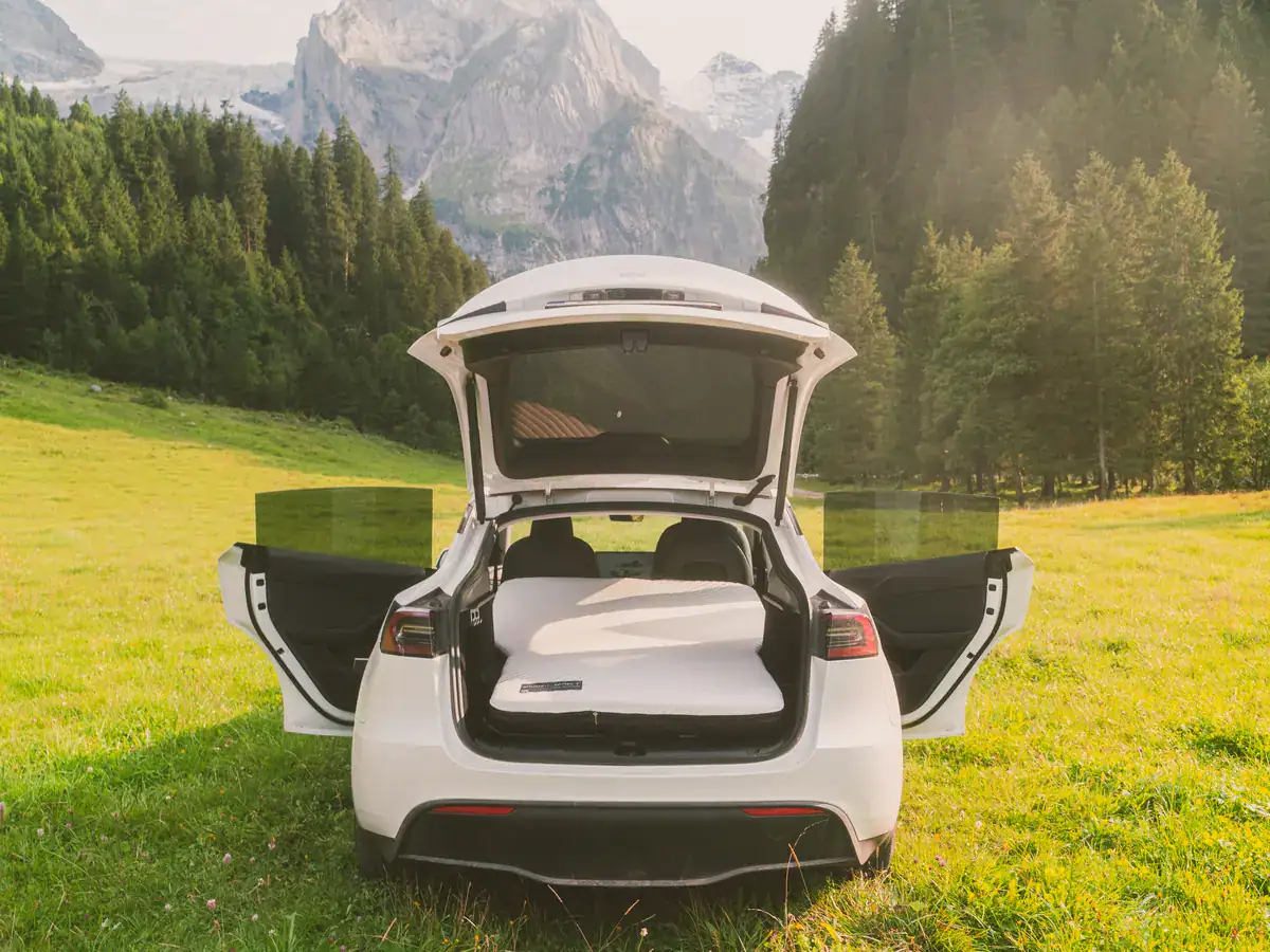 Tesla Model Y met open achterklep en Snuuzu-matras op een bergweide