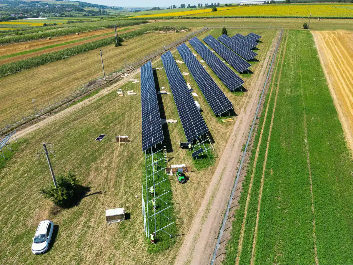 Parc fotovoltaic pe sol în execuție, văzut din dronă, cu echipa montând structurile
