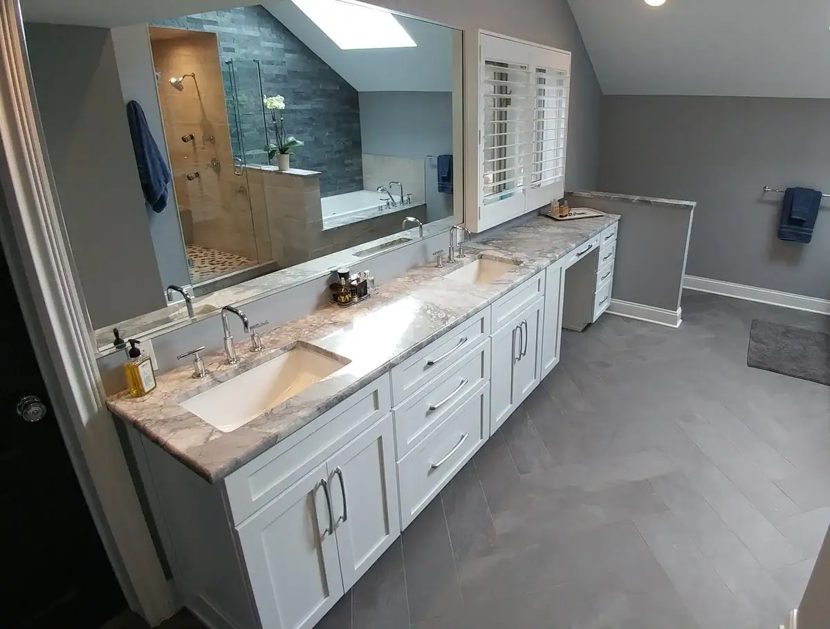 Modern bathroom featuring gray tiled floor, gray walls, white cabinets, and a shuttered window above the vanity.