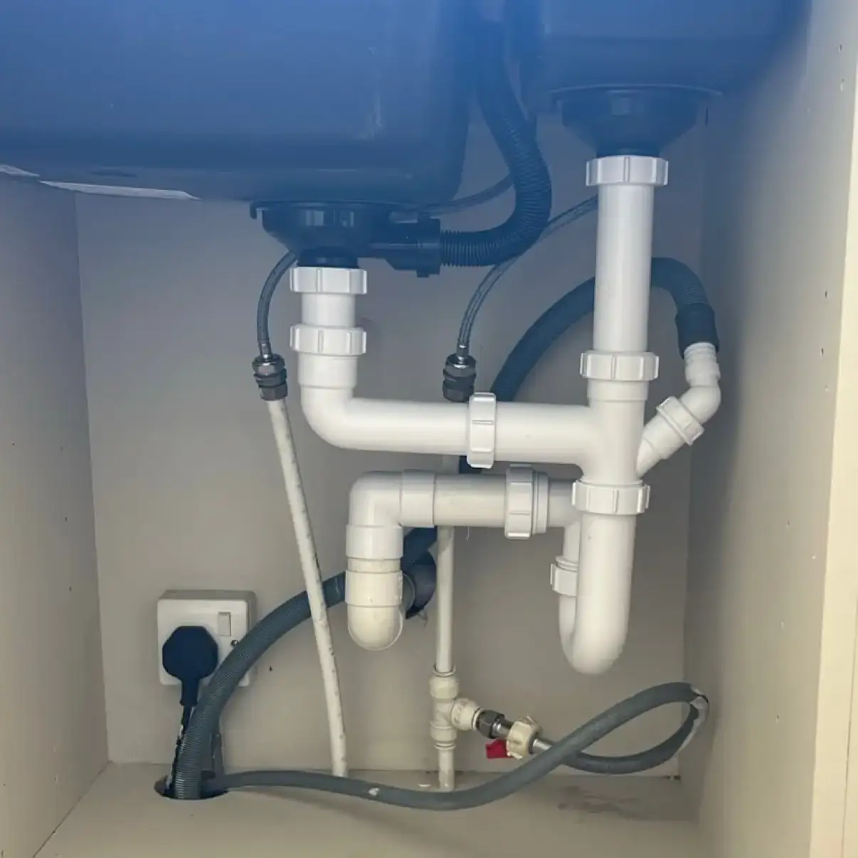 Clean under-sink plumbing installation showing a newly fitted double-bowl kitchen sink waste kit and pipework, completed by NB Gas & Plumbing in Cumbernauld, Glasgow
