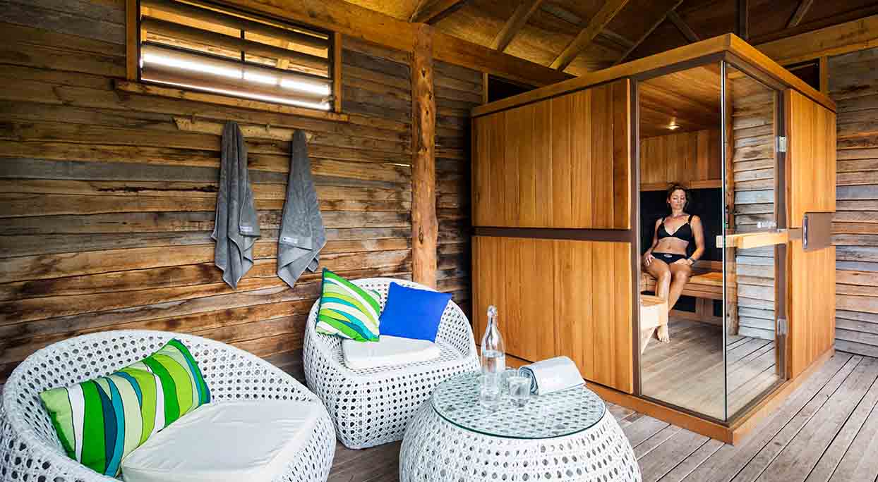 Une femme en maillot de bain est assise sur le banc d'un sauna infrarouge.
