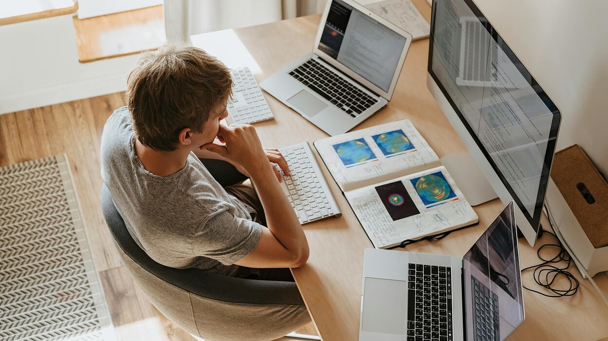 high angle shot of a boy sitting on grey chair while using his laptop computers