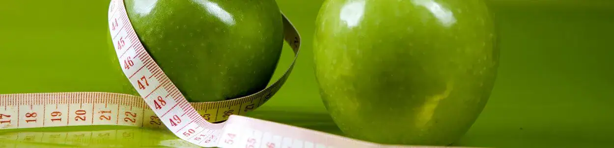 measuring tape around green apples