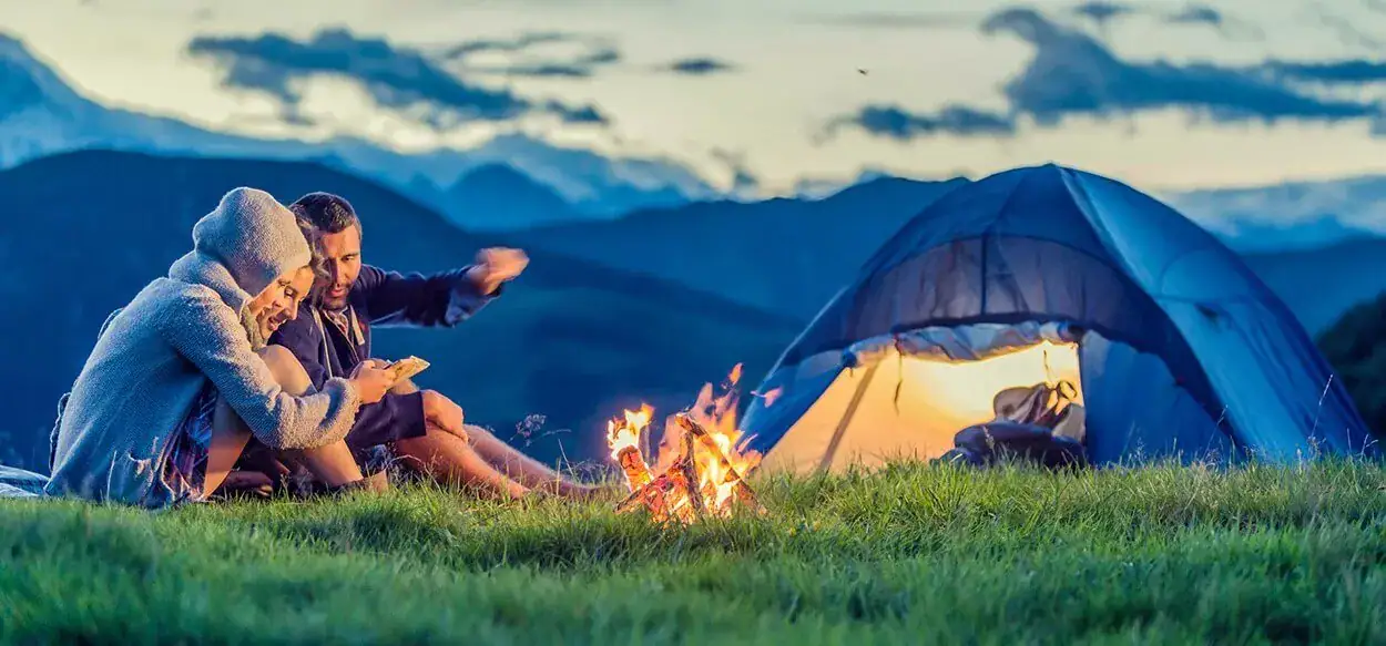 Three friends camping on mountain at sunset