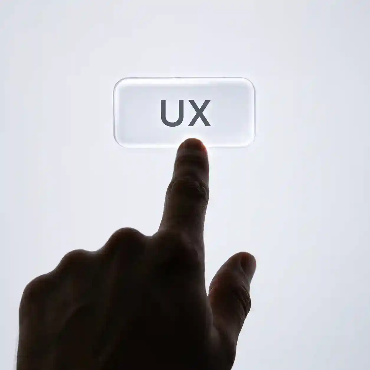 Una mano presionando un botón en una pantalla, que dice UX