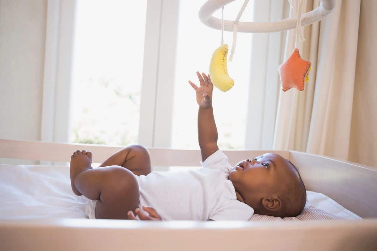 baby playing with hanging stars in their crib