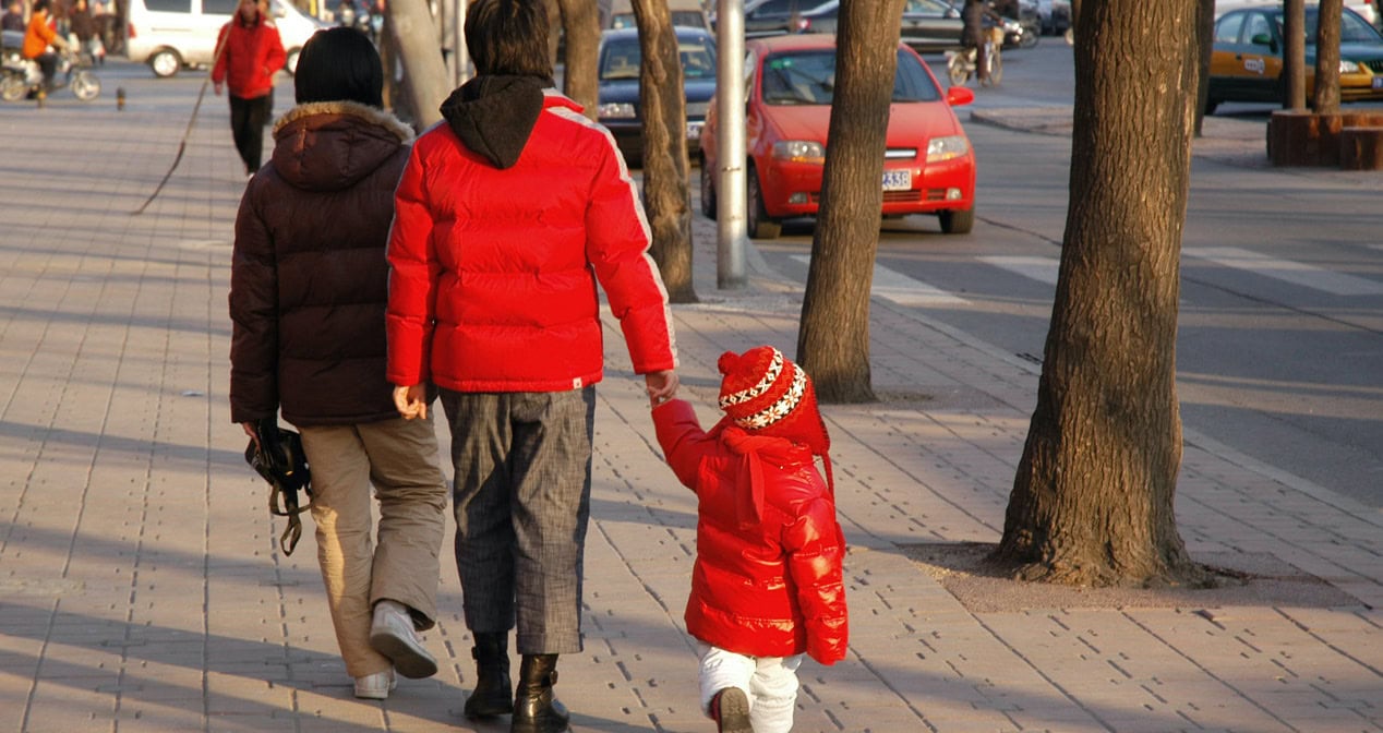 A parent walking away from camera holding the hand of their child, all in red | Bishop Hamilton Montessori School in Ottawa