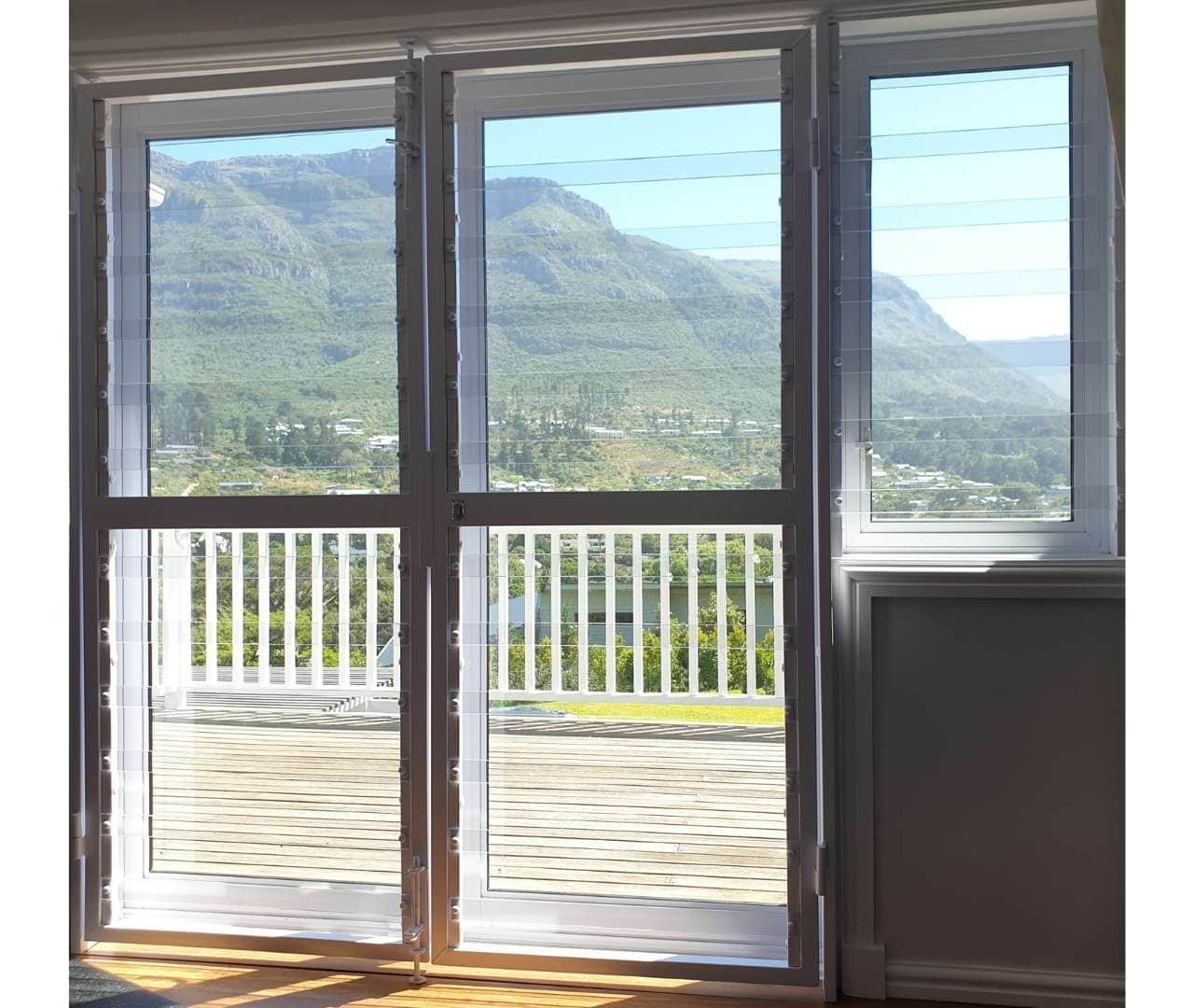 Interior view of clearview gate securing double French patio doors with transparent horizontal bars and panoramic mountain backdrop.