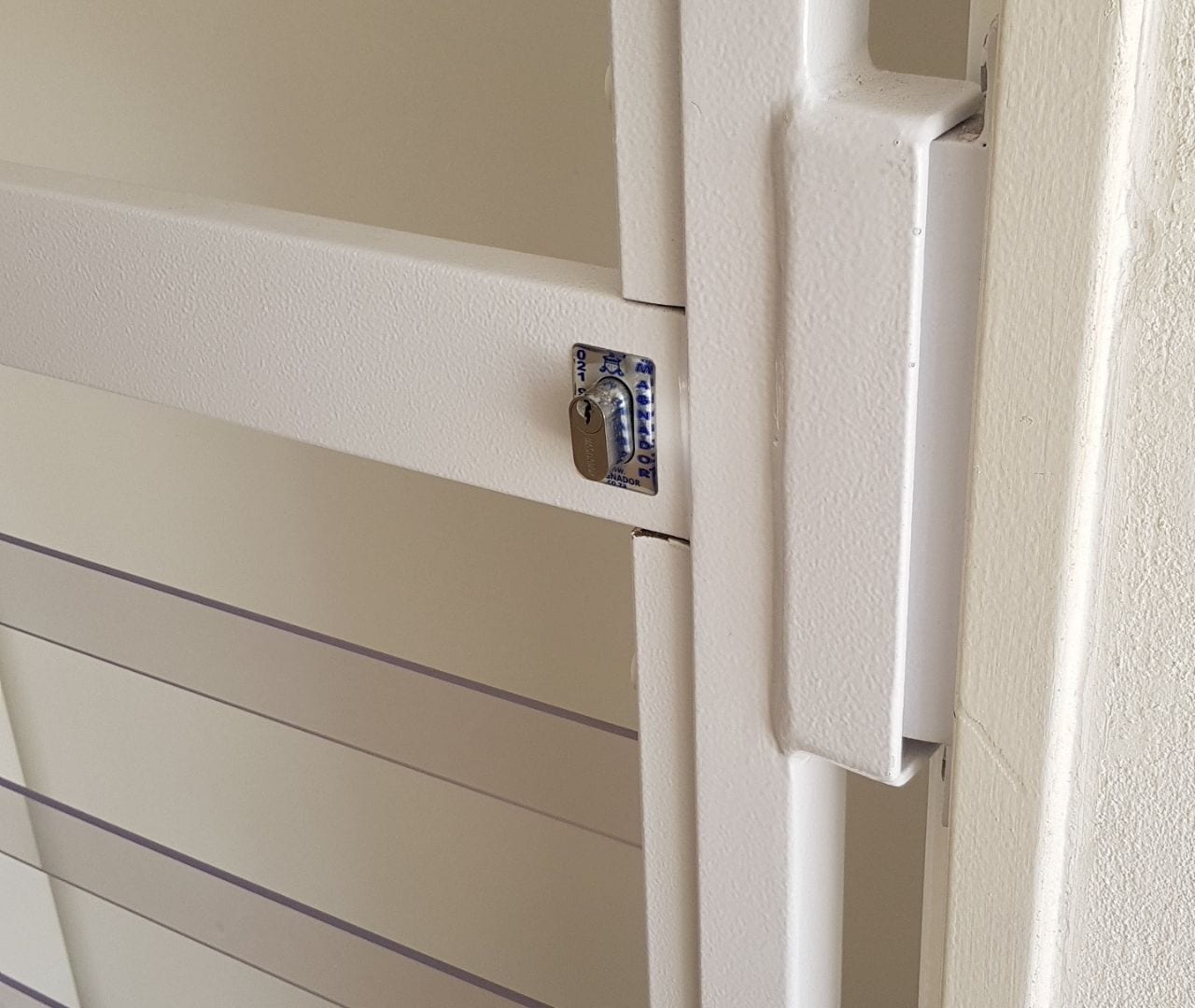 Close-up of clearview gate keyed lock and white steel frame, highlighting robust security hardware.