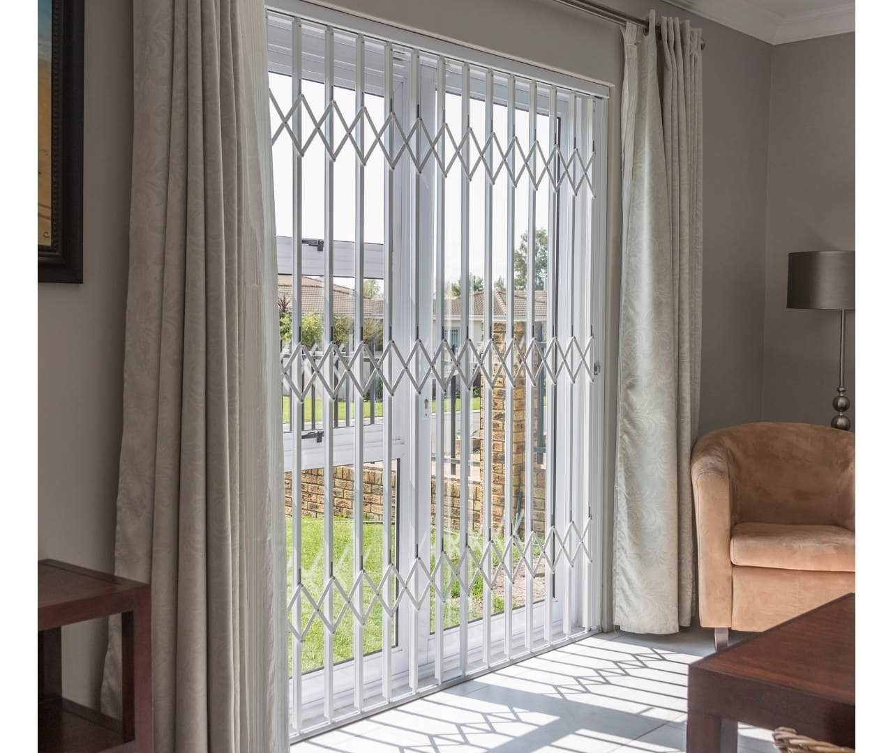 Living-room French doors secured by white retractable security gates, maintaining view to garden.