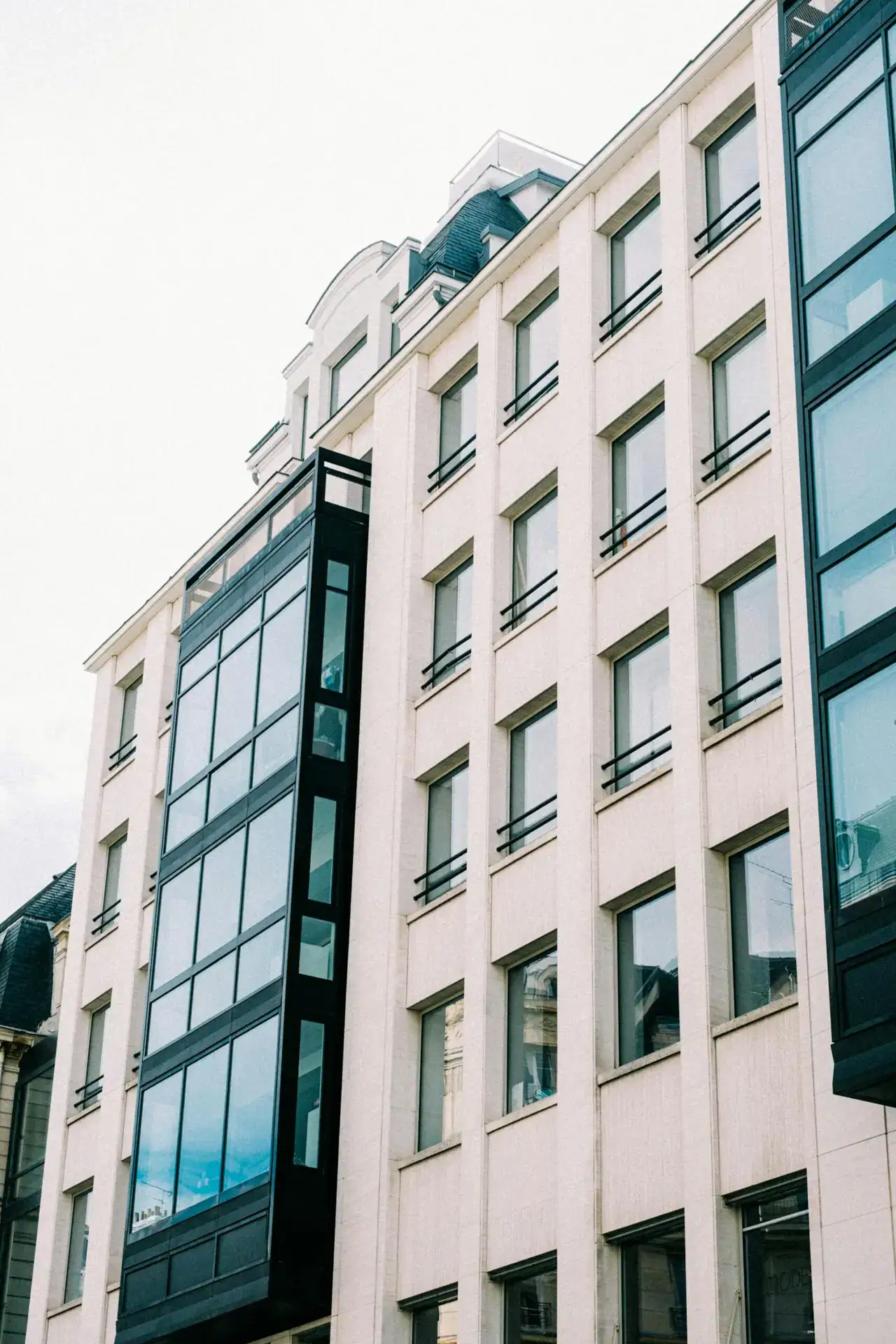 Low-angle view of a contemporary city building with glass and stone facade.