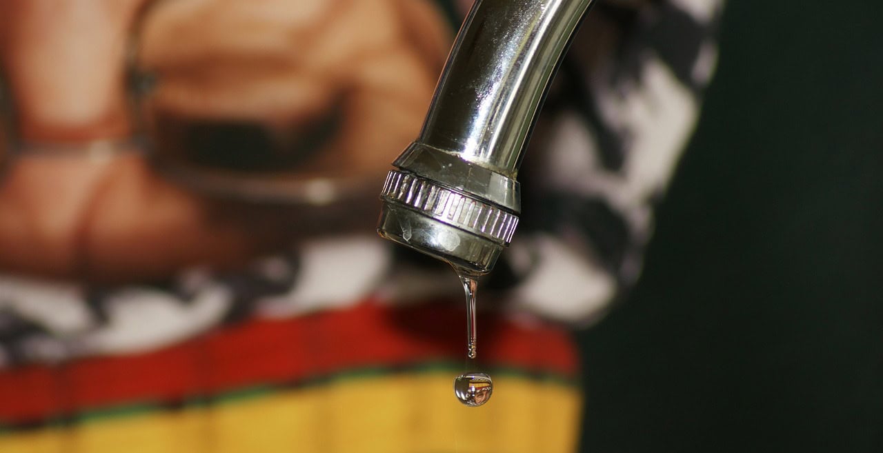 Leaking tap. Drip coming down from head. Blurred background.