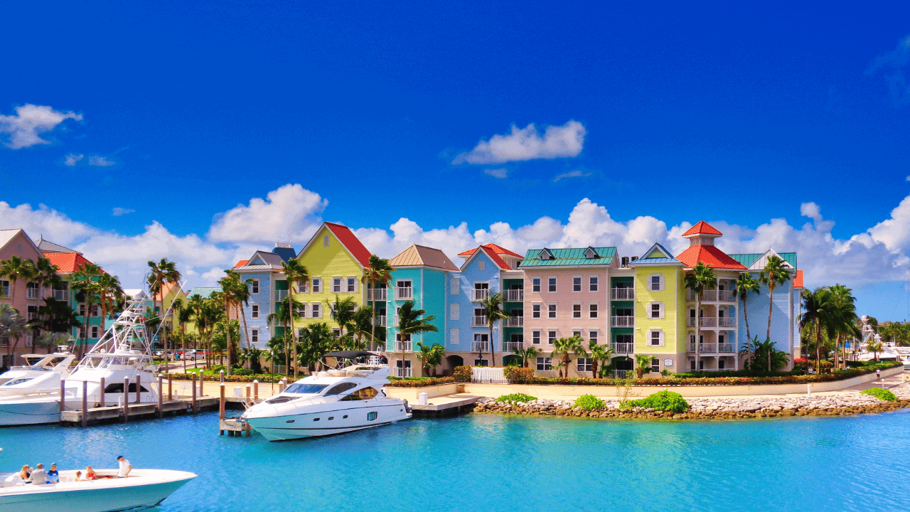 Colorful waterfront vacation condos with boats and palm trees in a vibrant tropical setting.