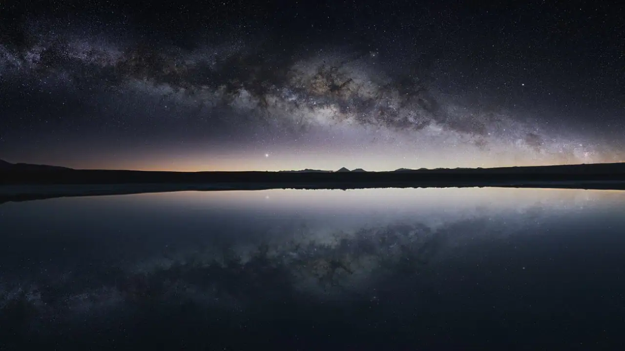 Reflexo perfeito da Via Láctea em uma lagoa no Deserto do Atacama, criando uma paisagem celestial única e deslumbrante.