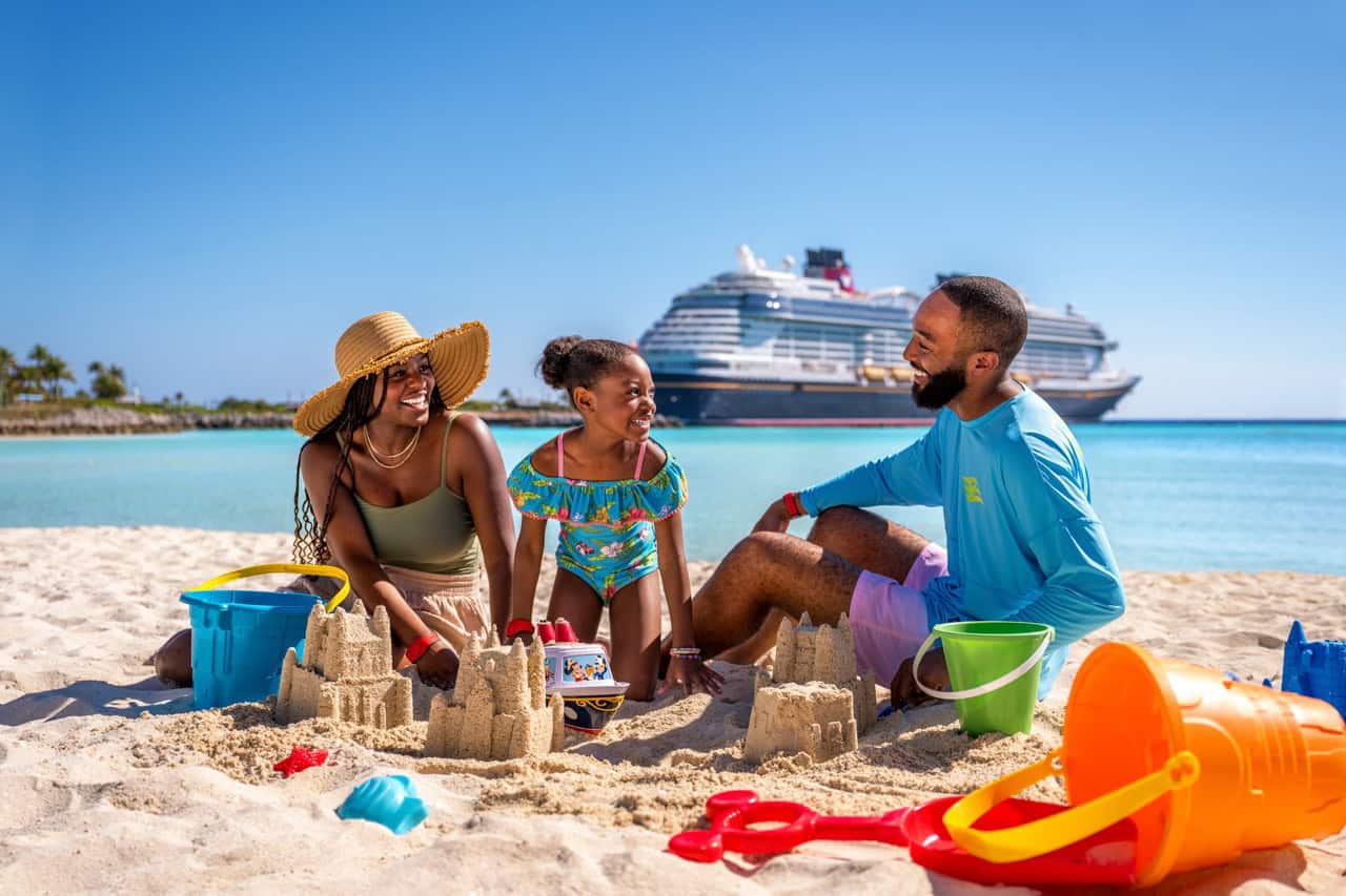 Vacation family building sandcastles on the beach with cruise ship in the background.