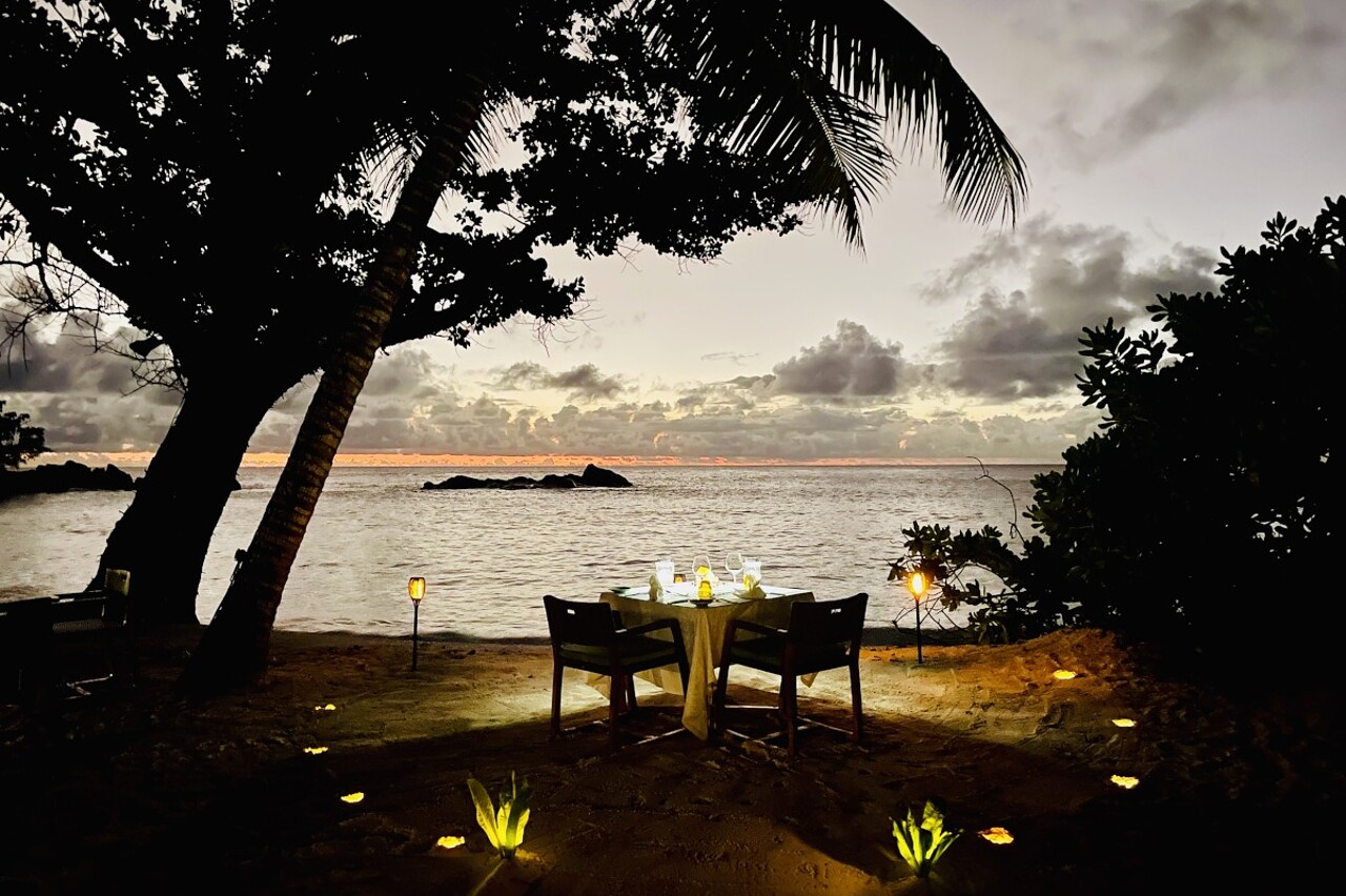 beach_dinner_petite_anse_kerlan Two-seat dining table by the beach after sunset