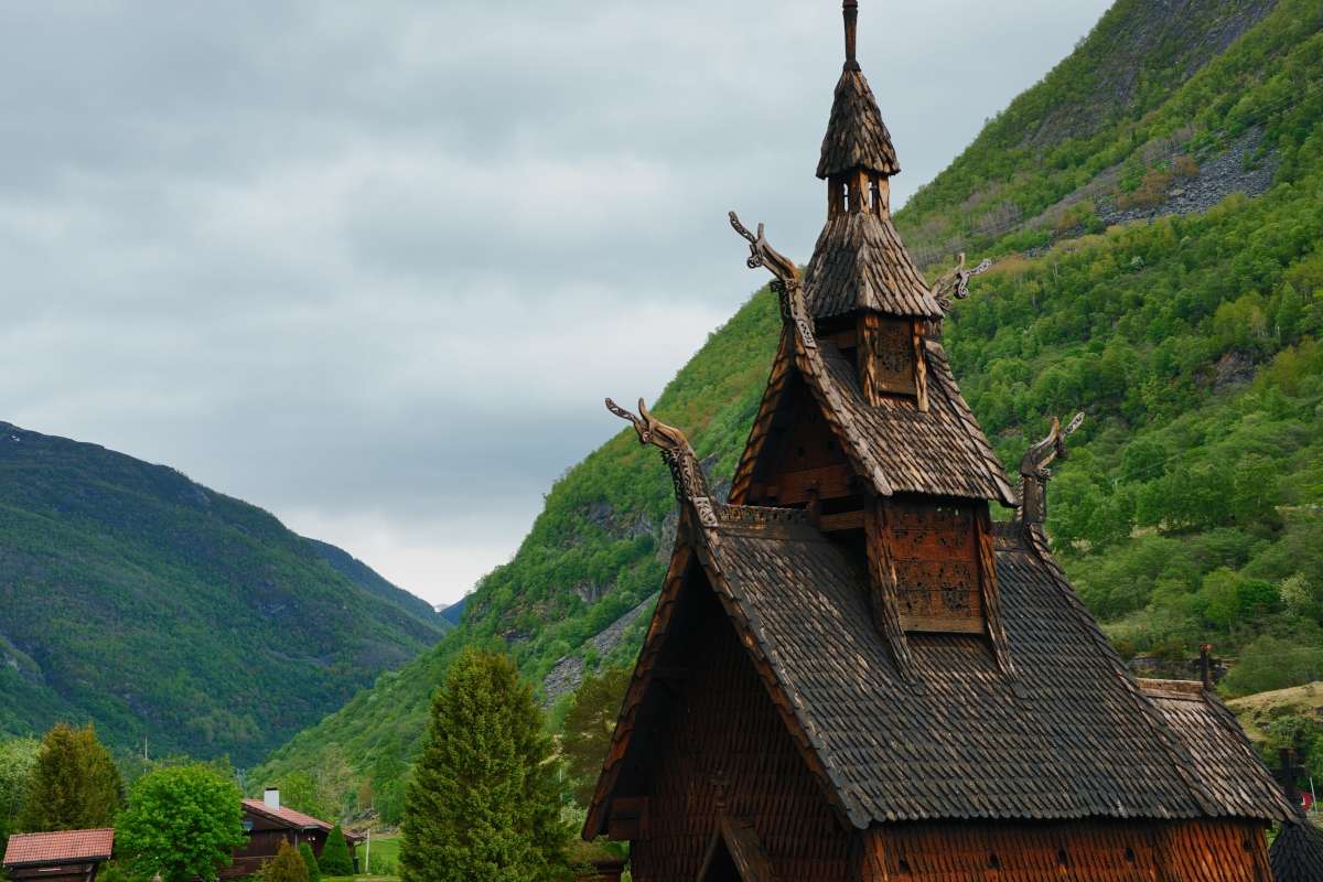 Roof details of wooden church in norway, with a background of green mountains