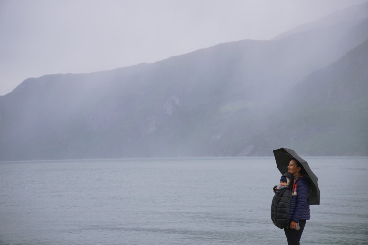 Mother and baby under an umbrella looking at a fjord