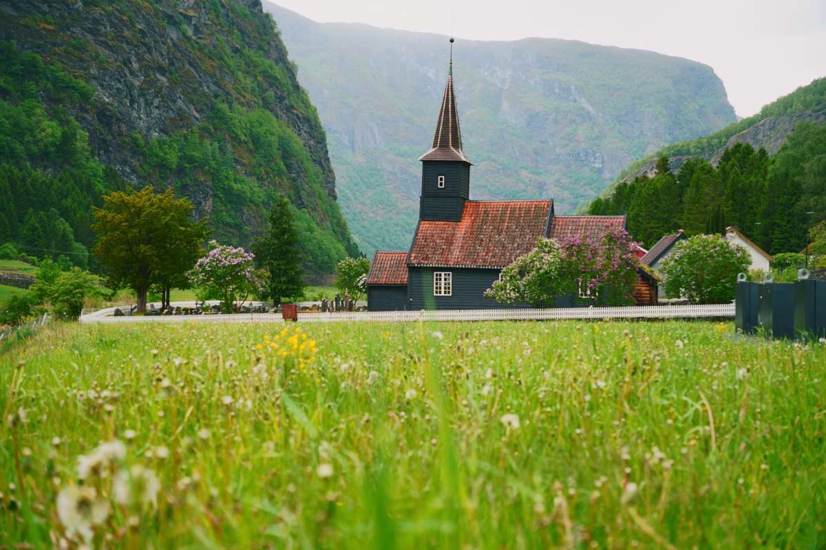 View of flam church in a meadow surrounded by mountains, norway