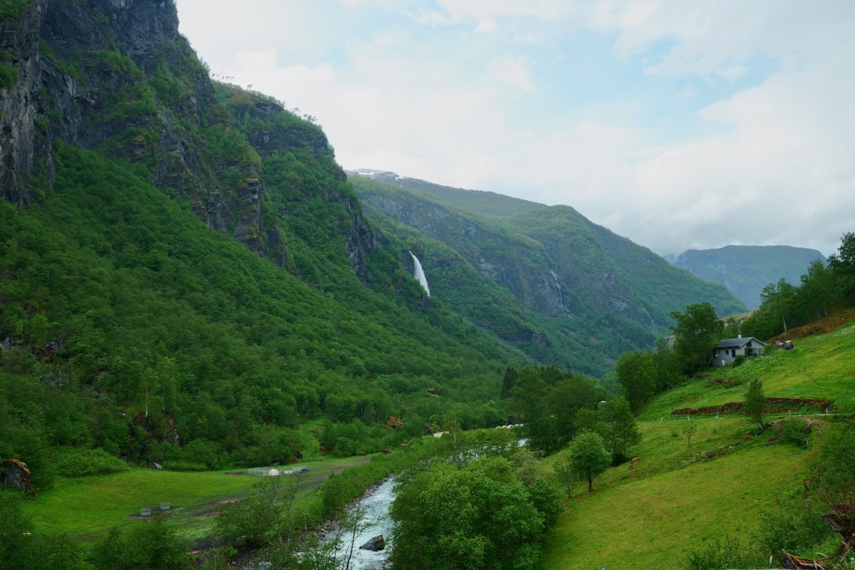 Water stream between leafy mountains with a distant waterfall