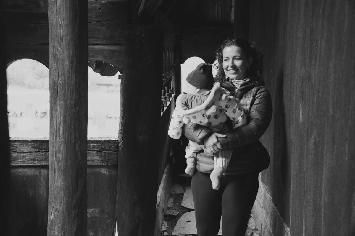 Black and white photo of mother and child walking underneath wooden pillars
