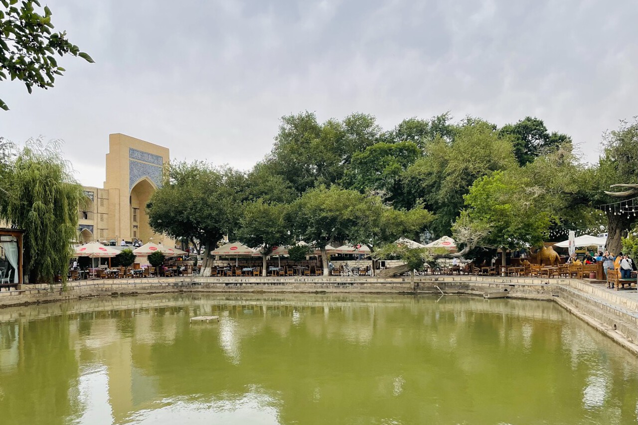 lyabi_khauz_square_bukhara water reservoir with trees and a madrasah on the background