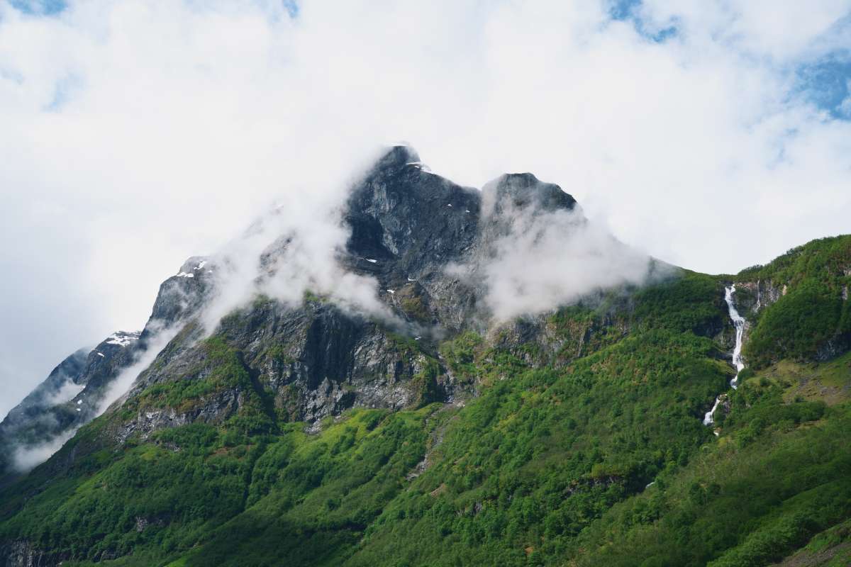 mountain_naerofjord_norway View of mountain in naeroyfjord with trees at the bottom and clouds surrounding the peak