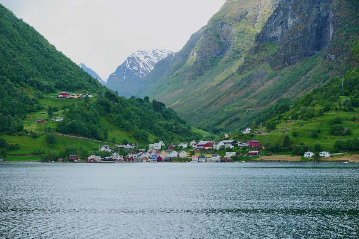 View of traditional fjord village from the water with mountains in the back, norway