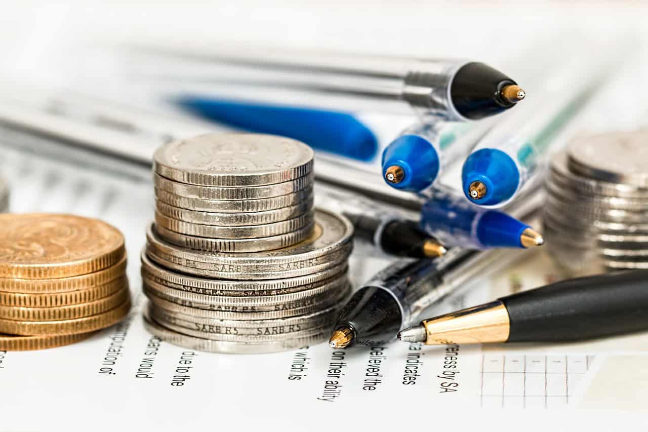 Financial analysis with coins and pens, symbolizing data-driven decision making and economic growth.